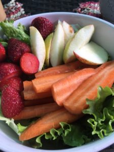 Raw fruit and veggie plate. Organic apples, carrots, strawberries on a bed of lettuce. 