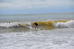 Me surfing in the green waves, standing up on my board and riding the wave in.